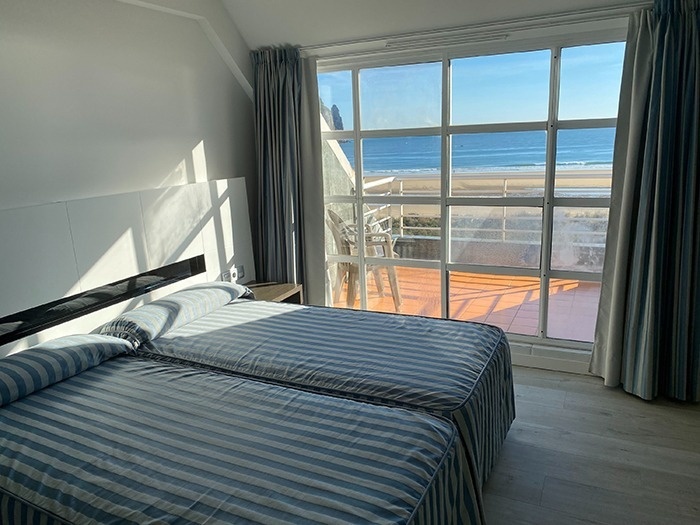 a bedroom with two beds and a balcony overlooking the ocean