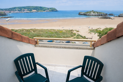 a view of the ocean from a balcony with two chairs