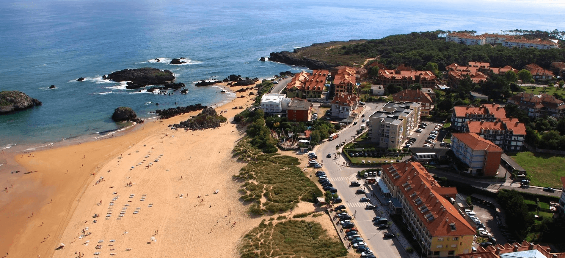 an aerial view of a beach with cars parked on the side of the road