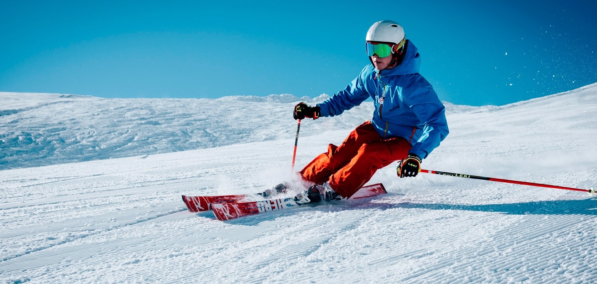 un esquiador con una chaqueta azul y pantalones rojos está esquiando por una ladera cubierta de nieve