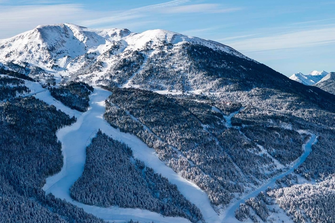 una pista de esquí rodeada de árboles y montañas cubiertas de nieve