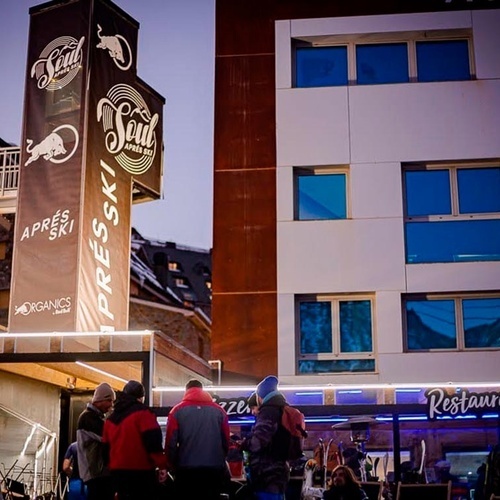 un grupo de personas se paran frente a un edificio con un cartel que dice apres ski