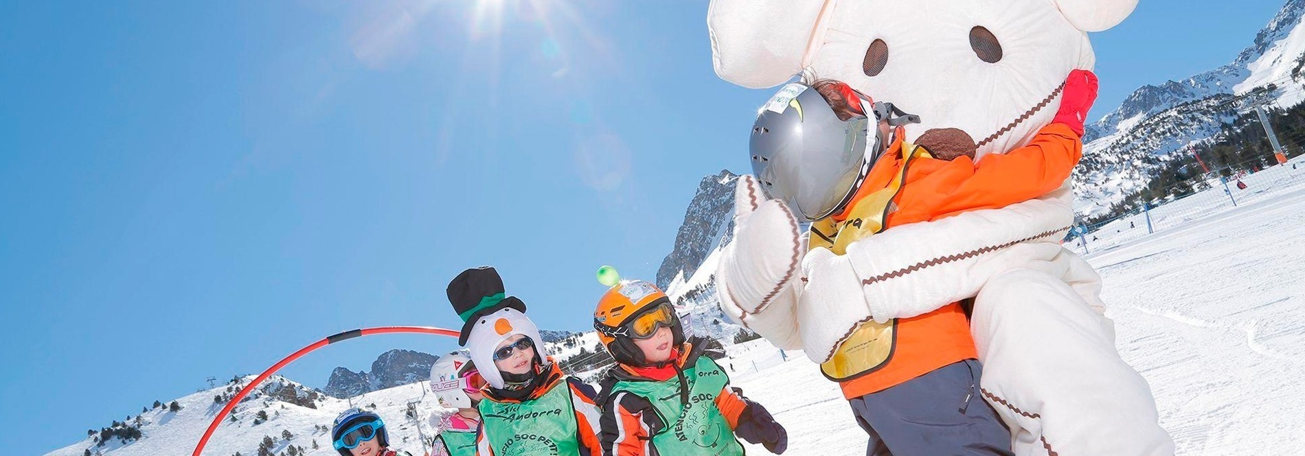 un grupo de niños con trajes de esquí y un oso de peluche en la nieve