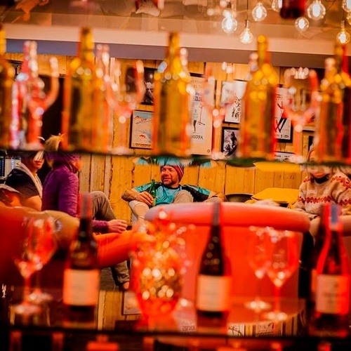 un hombre se sienta en un sofá con una botella de vodka en la mano