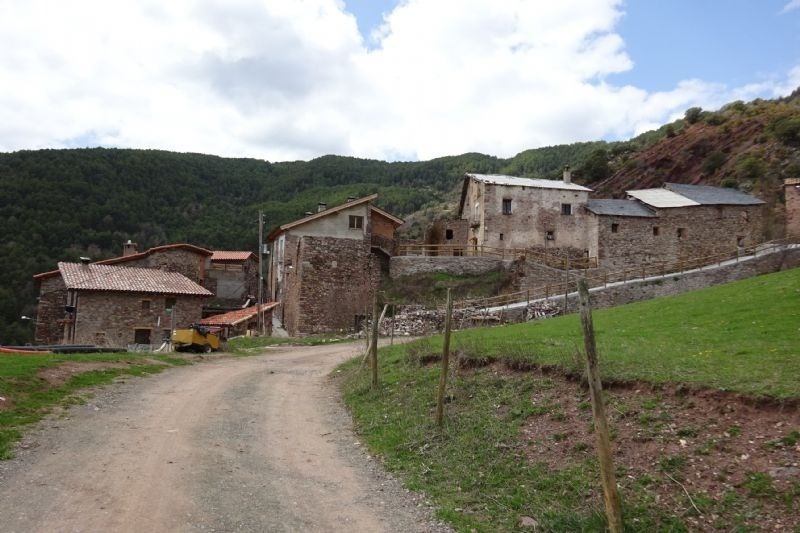 a dirt road leads to a small village in the mountains