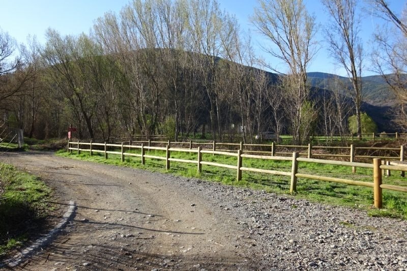 un camino de tierra con una cerca de madera a lo largo de él