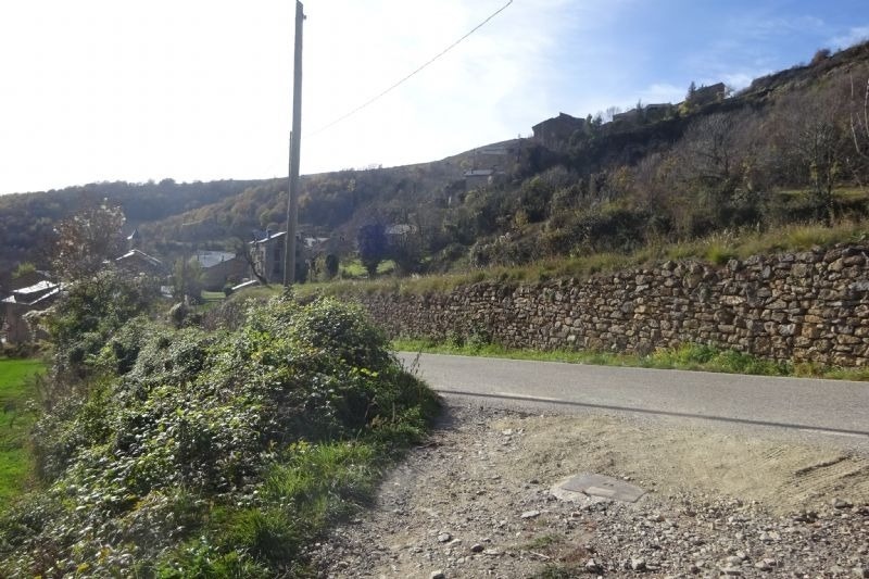 un camino de tierra con una pared de piedra al costado