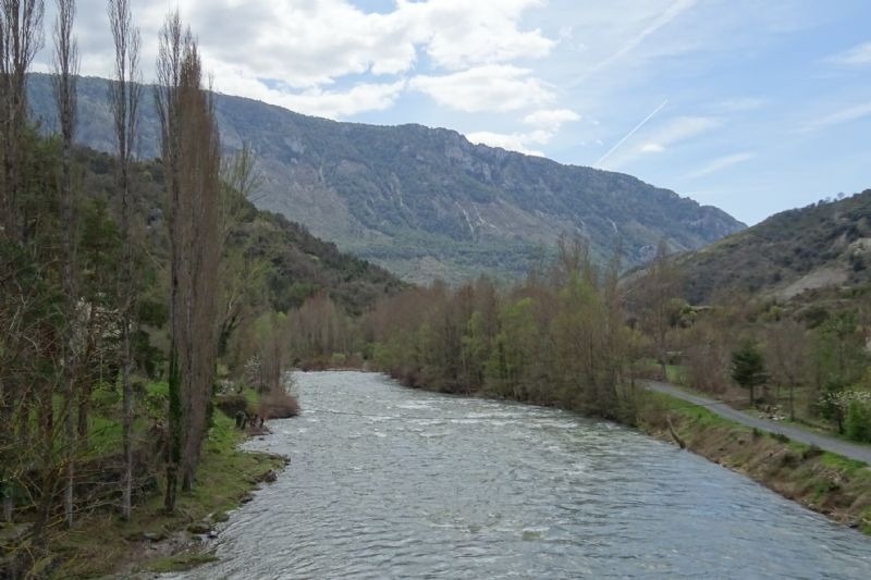 un río que fluye a través de un valle con montañas en el fondo