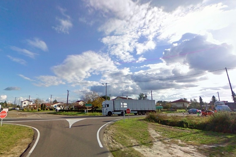 a white truck is driving down a road with a stop sign in front of it