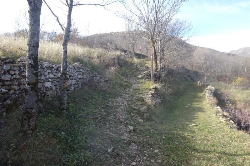 una persona camina per un sender de roca a la ladera d' una montagna