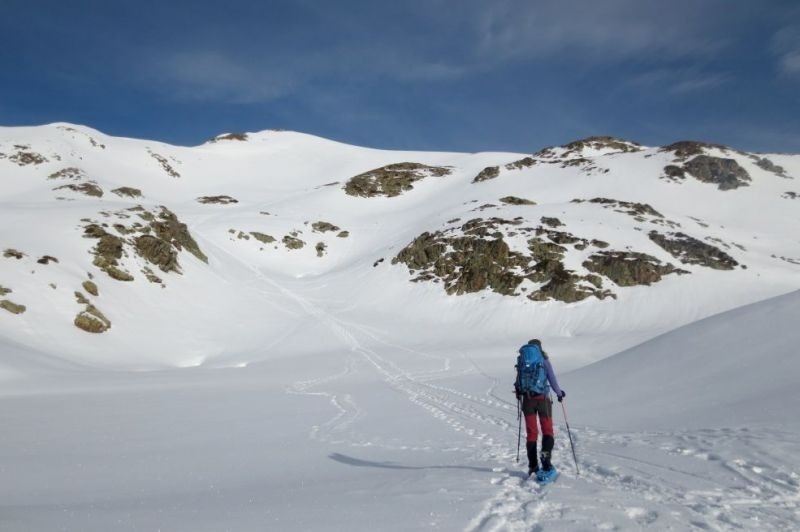 una persona amb una mochila azul camina en la nieve