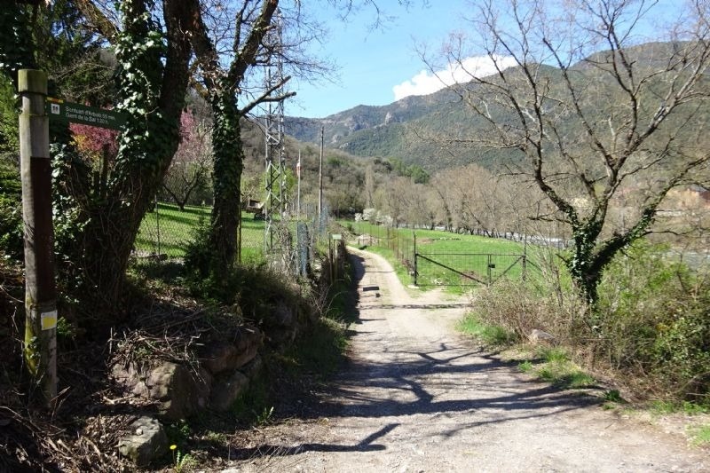 un camino de tierra que conduce a una puerta y un cartel que dice " sendero del parque "