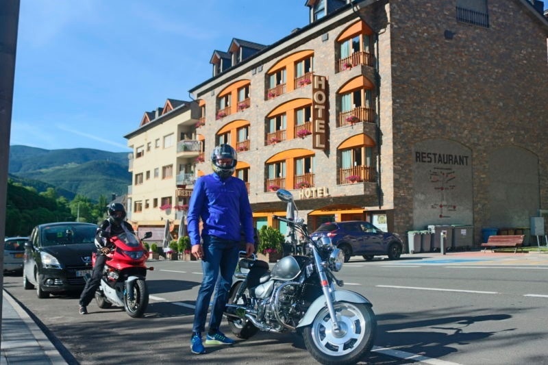 a man stands next to a motorcycle in front of a hotel