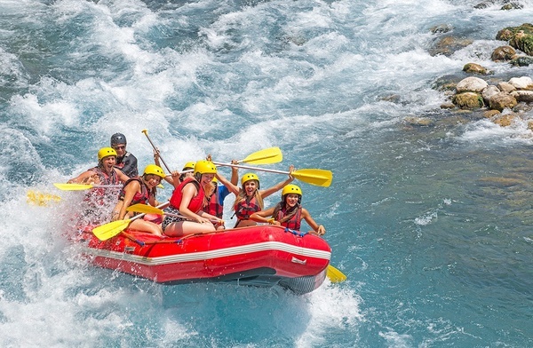 un grupo de personas están remando en un bote rojo en un río
