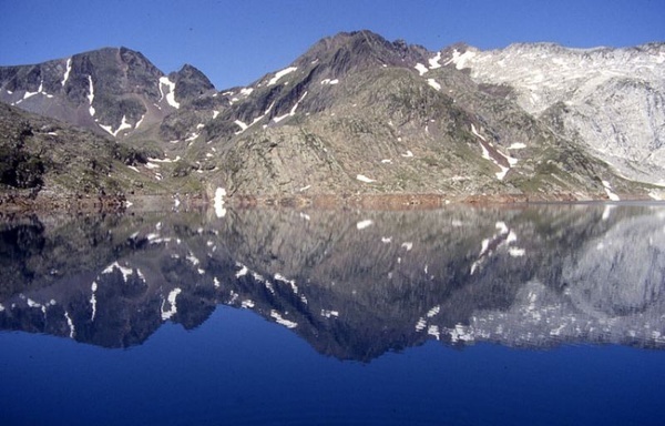 montañas reflejadas en un lago con un cielo azul