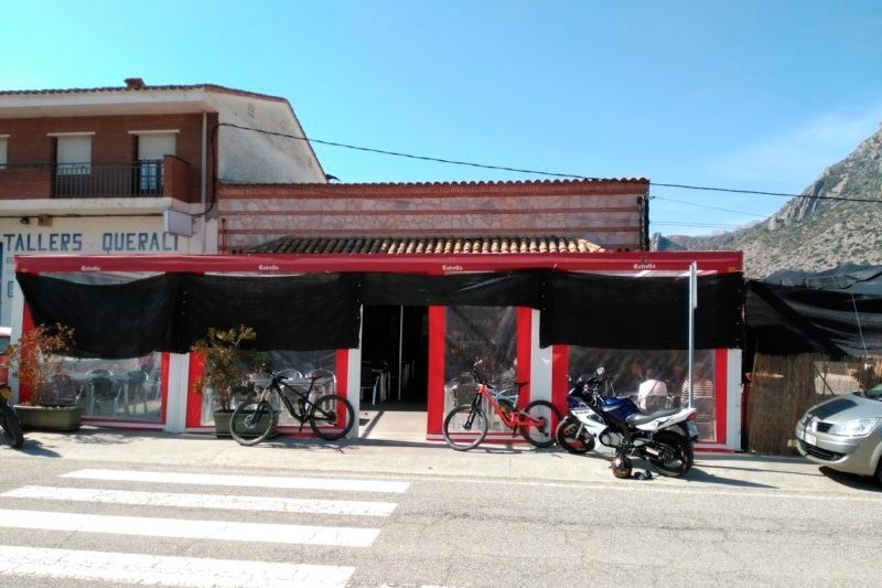 deux vélos sont garés à l' extérieur d' un bâtiment avec un panneau qui dit tallers queralt