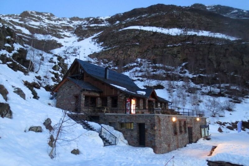 una casa de pedra a la ladera d' una montagna coberta de neige