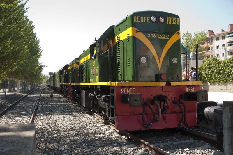 a green and yellow renfe train sits on the tracks