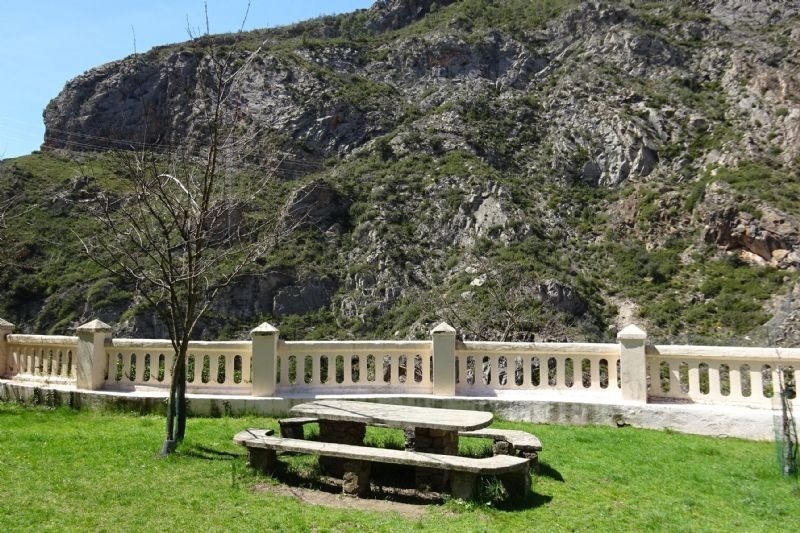 una mesa de picnic junto a una cerca con una montaña en el fondo