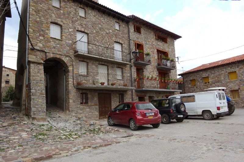 a red car is parked in front of a stone building