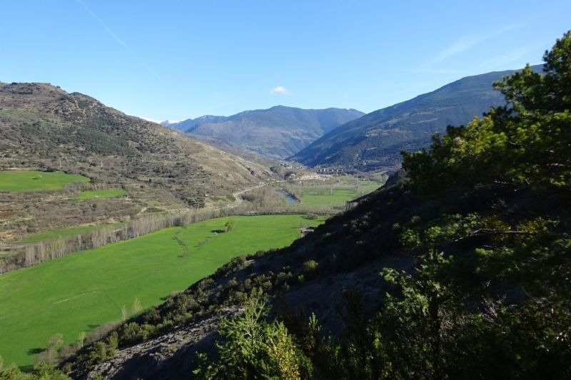 un valle con un río y montañas en el fondo