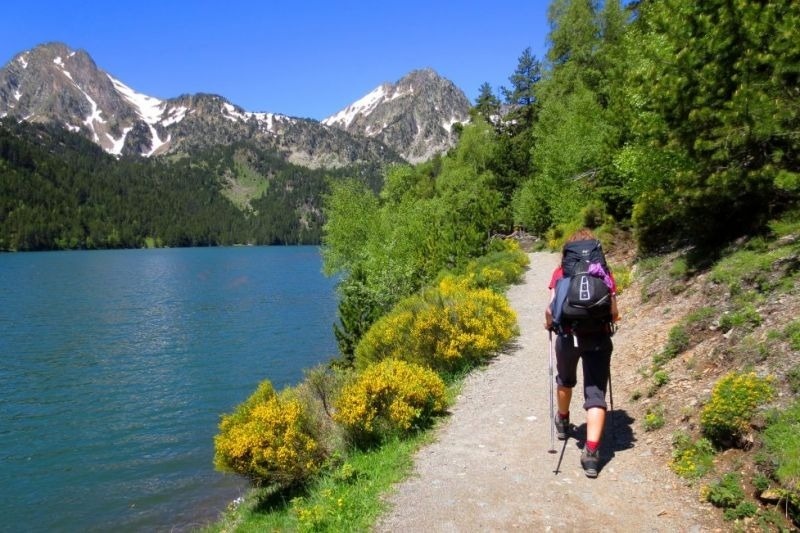 una persona con una mochila camina por un sendero junto a un lago