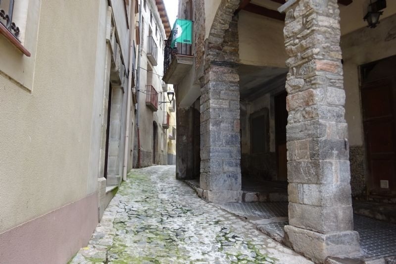 una calle estrecha con columnas de piedra y edificios
