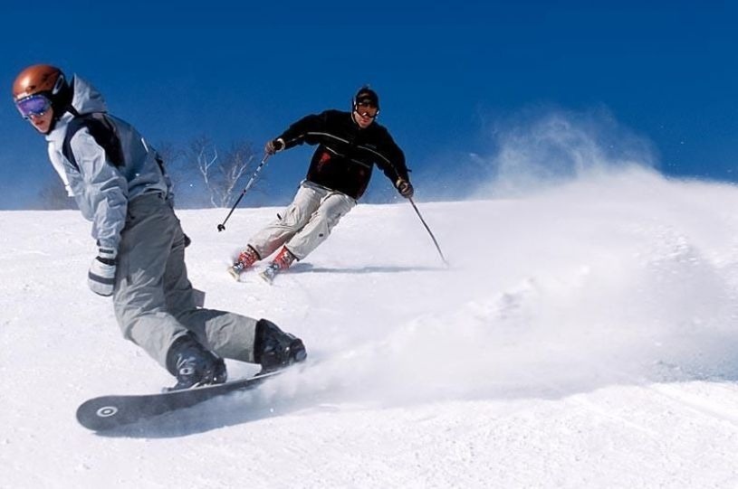un skieur et un snowboarder sur une pente enneigée
