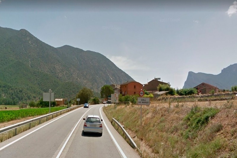 un coche conduce por una carretera con una señal que dice coll de les valls