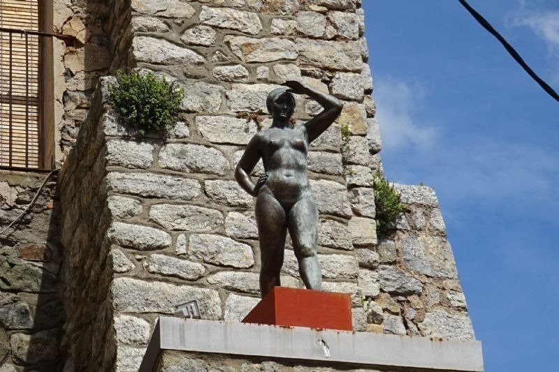 una estatua de una mujer sin camisa está encima de un pedestal rojo