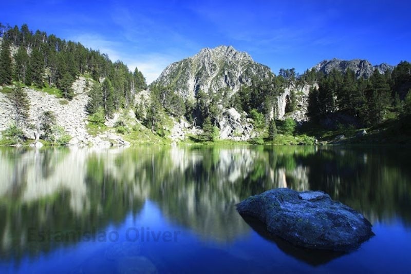un lago rodeado de montañas y árboles con la palabra oliver en el fondo