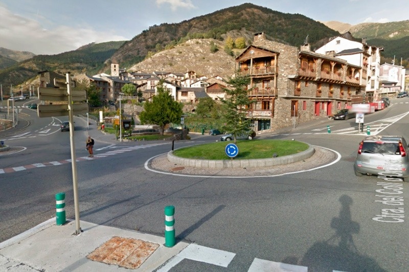 un cruce de carreteras con un edificio en la ladera de la montaña en el fondo