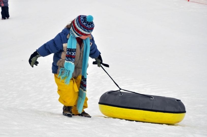 un enfant tire un tube jaune dans la neige