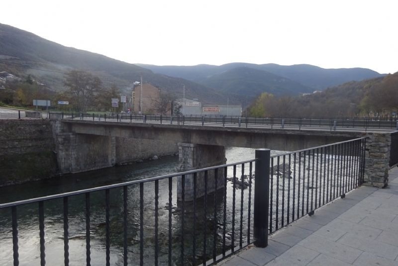 un pont a través d' un riu amb un edifici a l' altra banda