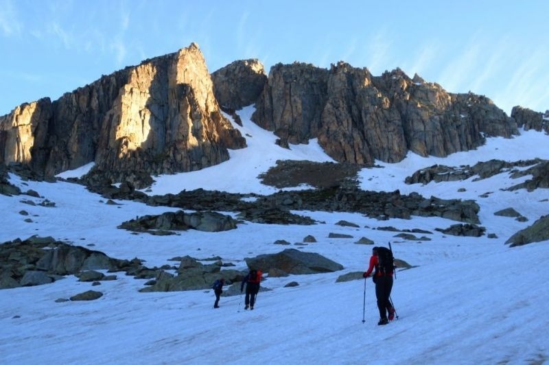 dos personas con mochilas y bastones caminan por la nieve hacia una montaña