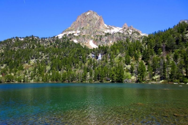 un lago en medio de un bosque con una montaña en el fondo