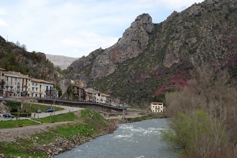 un pueblo junto a un río con montañas en el fondo