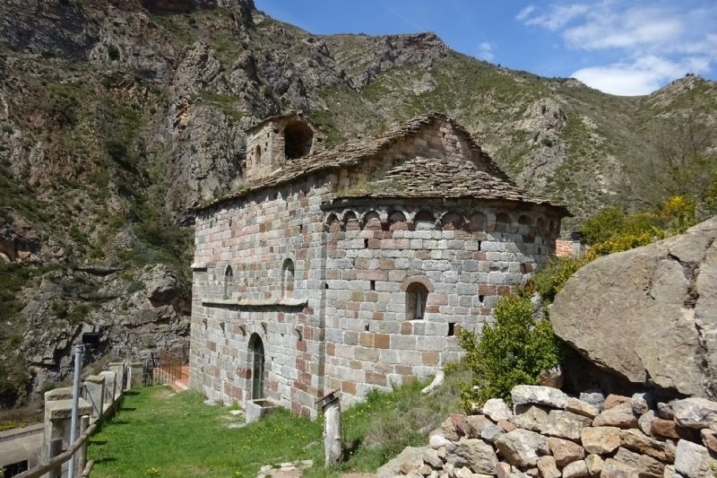 una antigua iglesia de ladrillo con techo de tejas está en medio de una montaña
