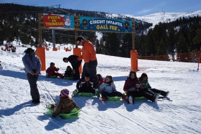 un groupe de personnes assises sur des traîneaux à côté d' un panneau qui dit pista de trineus