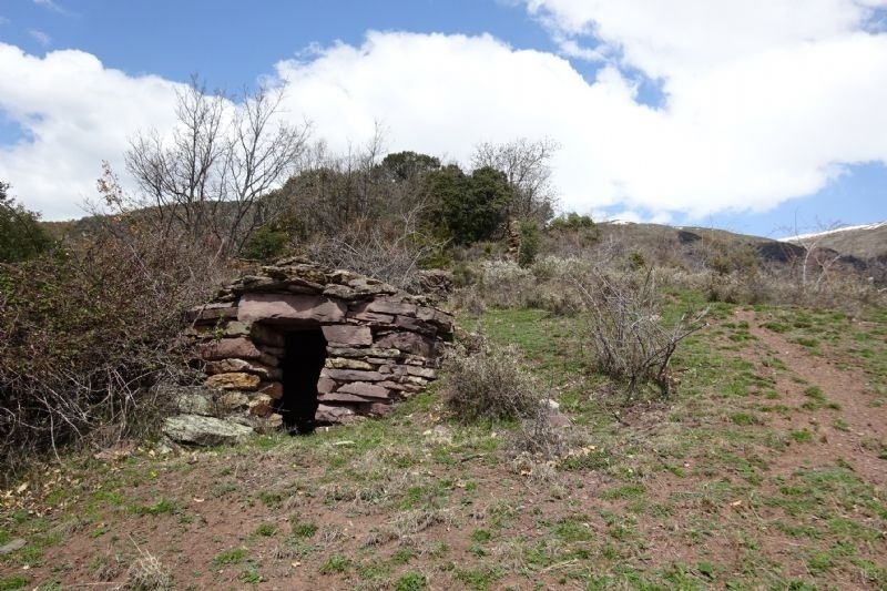 a stone structure in the middle of a grassy field