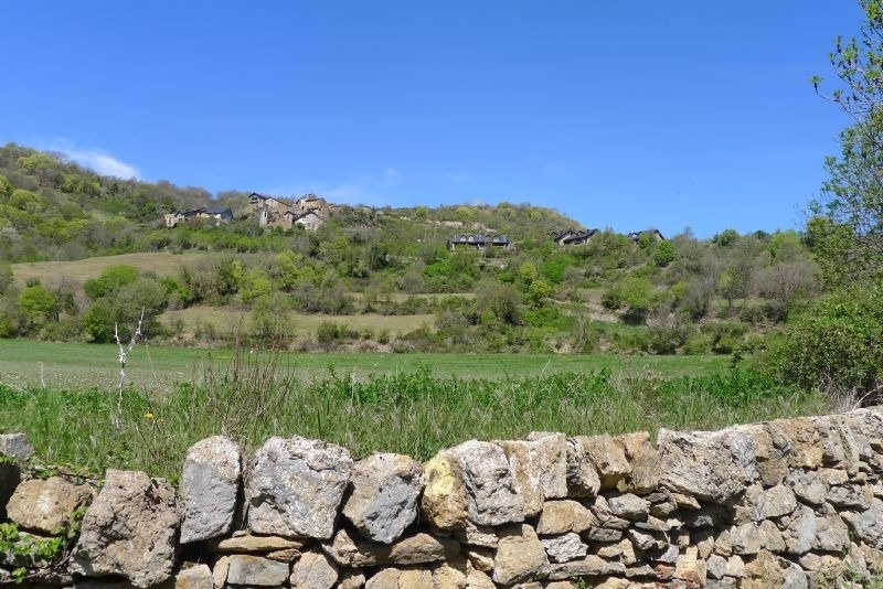 a stone wall with a view of a village in the background