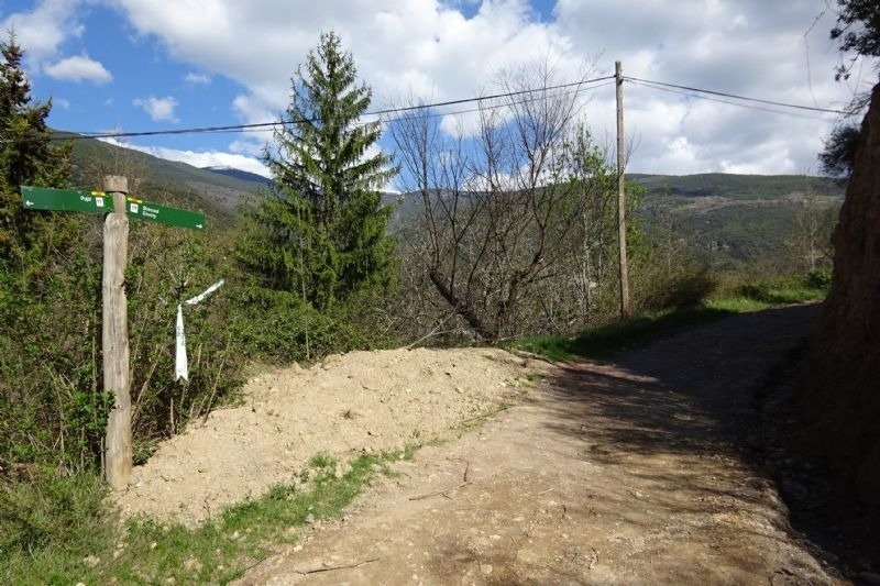 a sign on the side of a dirt road shows the way to the mountains