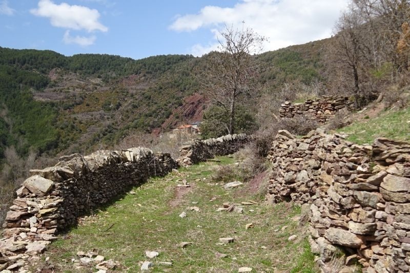 a stone wall along a path in the mountains