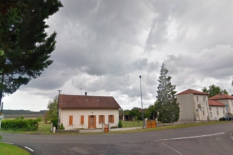 a house with a red roof sits on the corner of a road