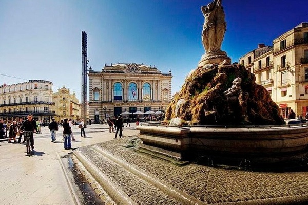 a man is riding a bike in front of a fountain with a statue on top of it