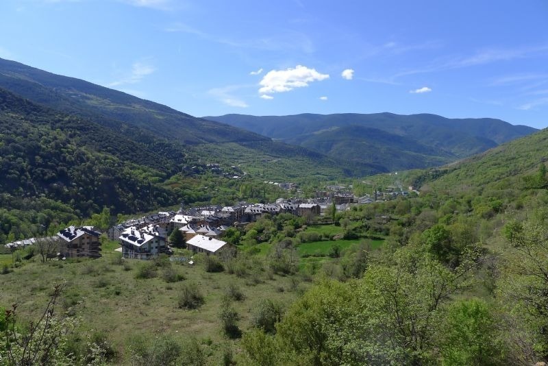 a village in the middle of a valley with mountains in the background