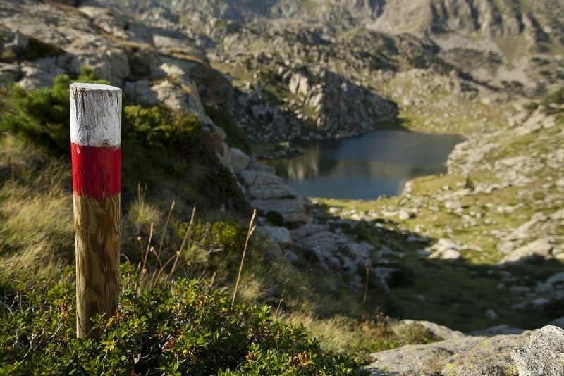 un poste de madera rojo y blanco con un lago en el fondo