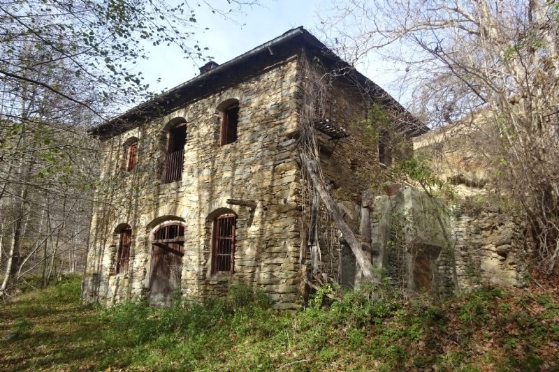 un antic edifici de pedra cobert d' arbres i vegetació
