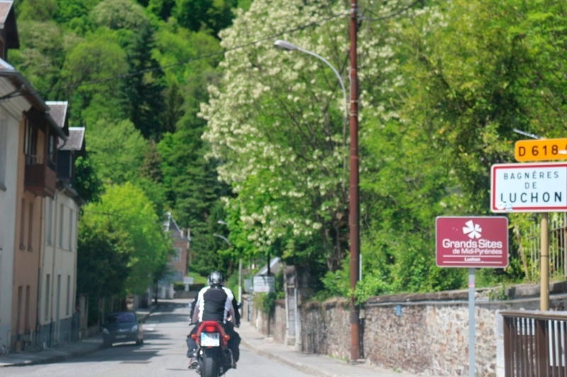 un homme sur une moto passe devant un panneau indiquant les grands sites de midi-pyrenees