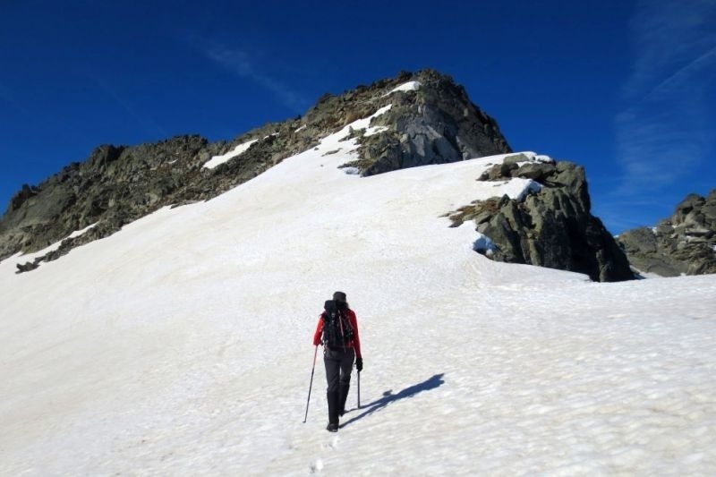 una persona con una mochila camina por la nieve en una montaña